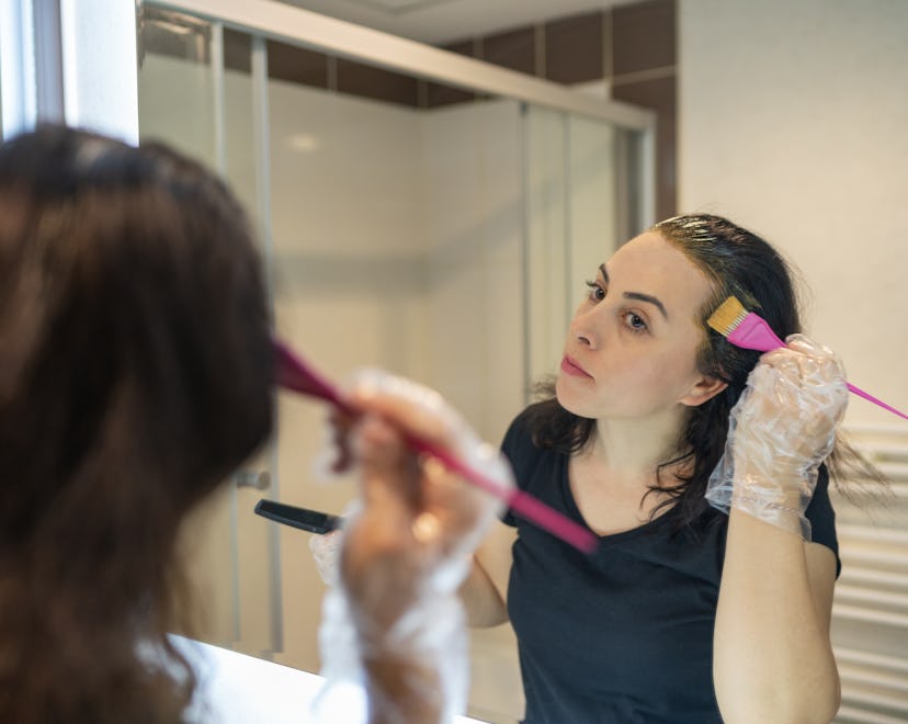 woman looking in the mirror, coloring her own hair