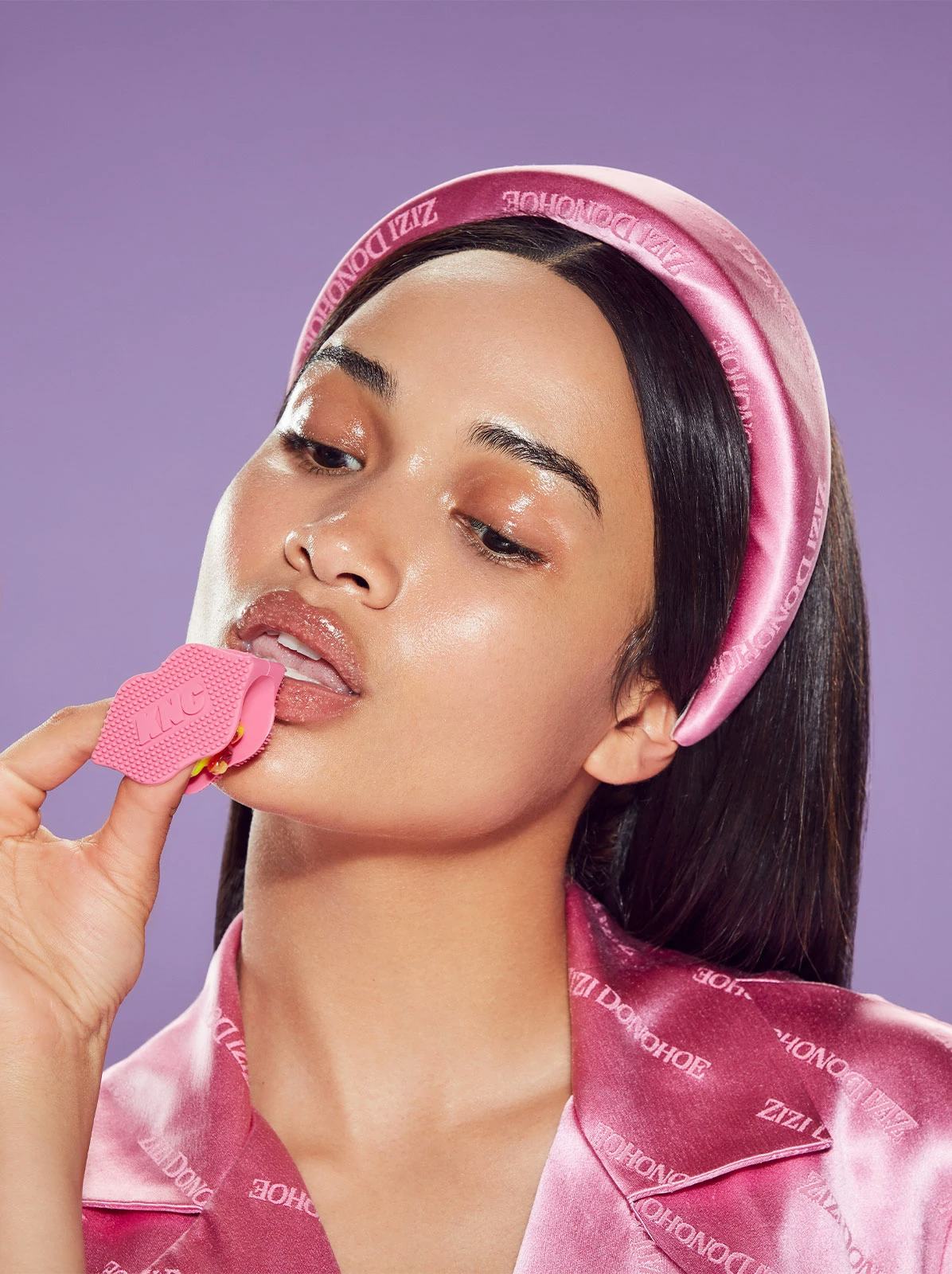 A model with glossy skin applies the KNC lip scrub.