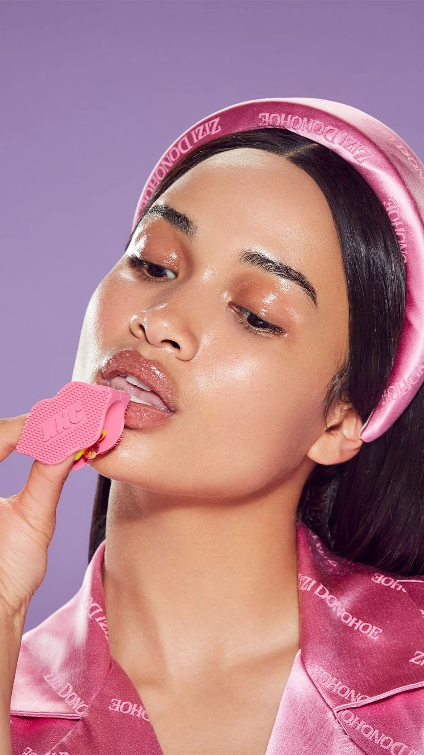 A model with glossy skin applies the KNC lip scrub.