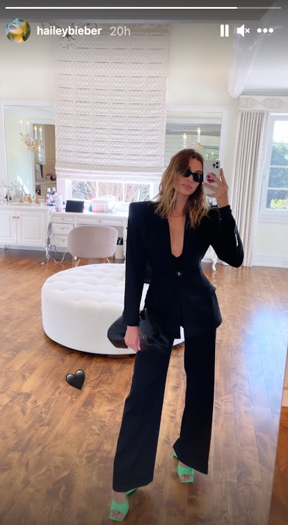 Hailey Bieber posts to Instagram Stories while wearing an Attico black blazer and pants combination.