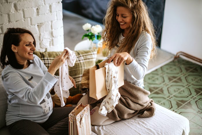 two friends opening baby presents on the couch