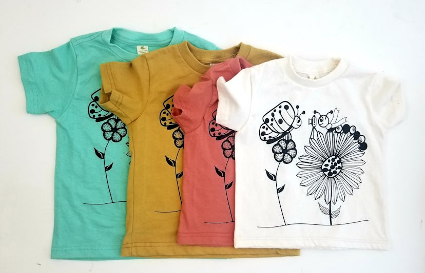 Four tee-shirts, each in a different size and color (white, red, mustard, and teal) with a black and...