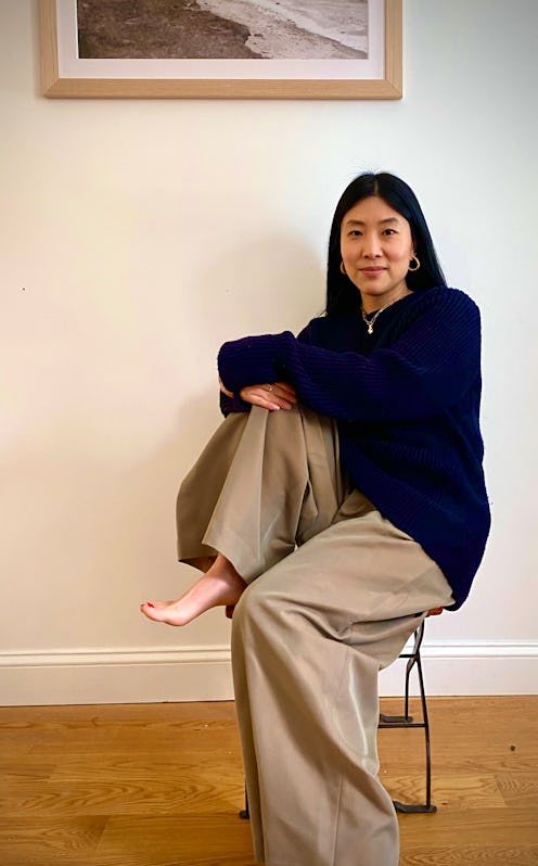 A woman sitting in a black hoodie and beige wide leg pants