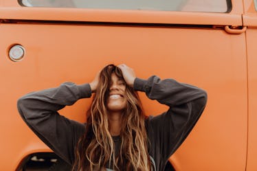 Happy young woman in front of orange car
