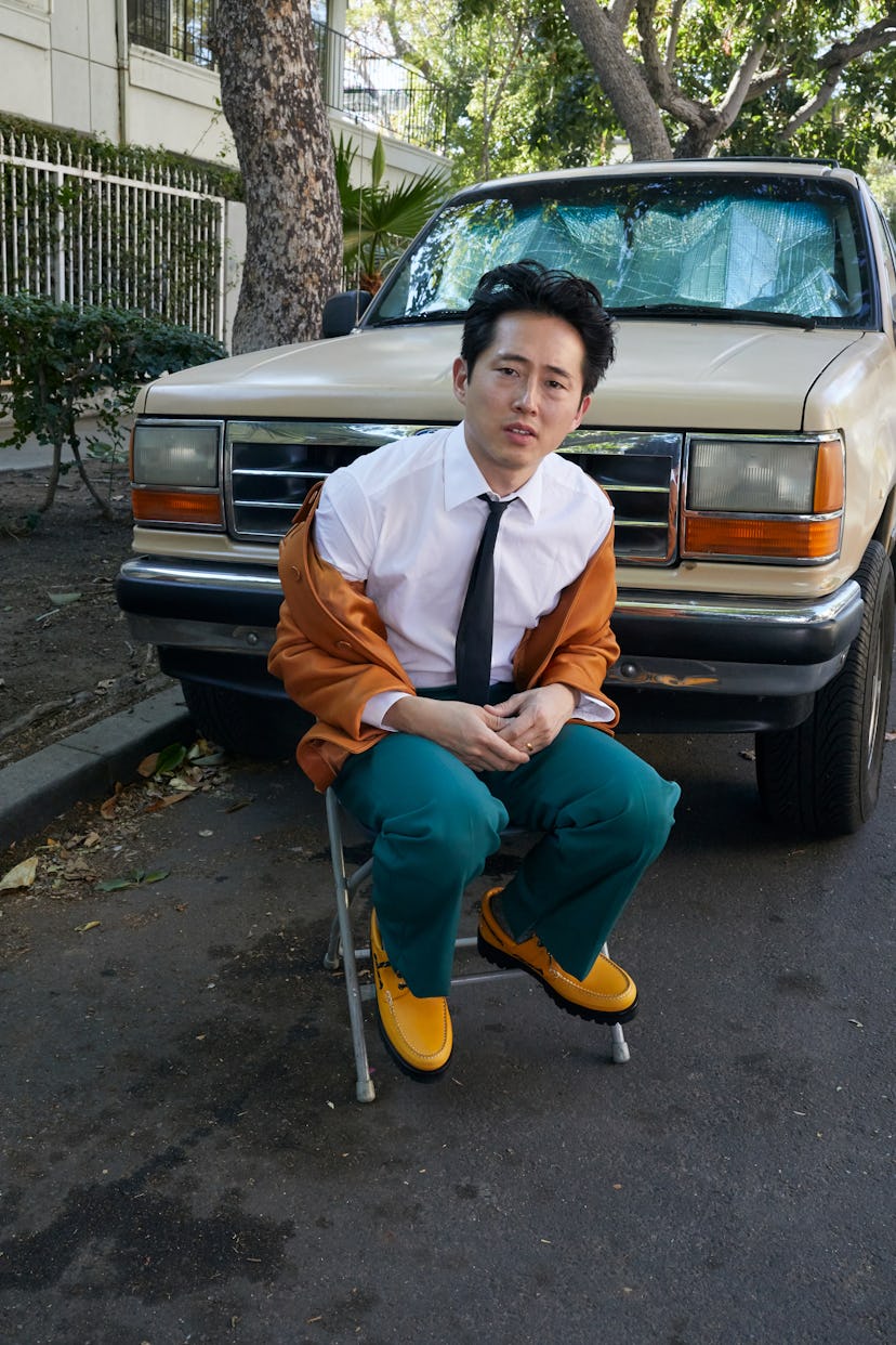 Steven Yeun wears a Louis Vuitton Men’s jacket, shirt, pants, tie, and shoes; Falke socks; his own r...