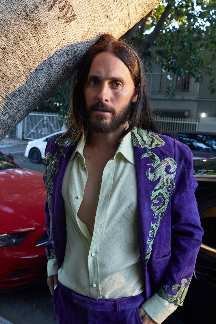 Jared Leto in a purple blazer and pants with snakeskin detailing, and a beige shirt unbuttoned to th...