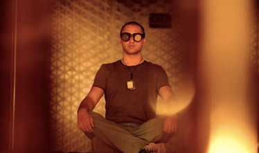 Cliff Curtis sitting cross-legged with goggles on.