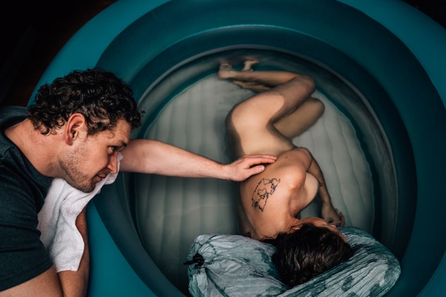 A man leans his head on the side of an inflatable swimming pool as he reaches out one hand to touch ...