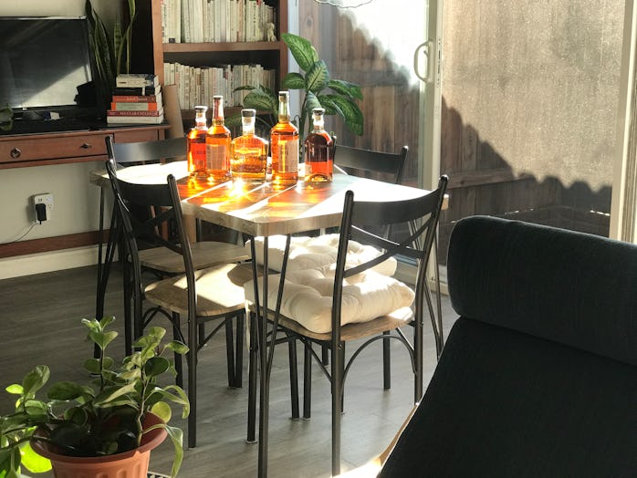 A dining table near a patio can be seen. There are five bottles of whiskey on top of the table. The ...