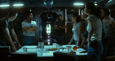 Seven cast members stand around a brightly lit table and argue in Sunshine