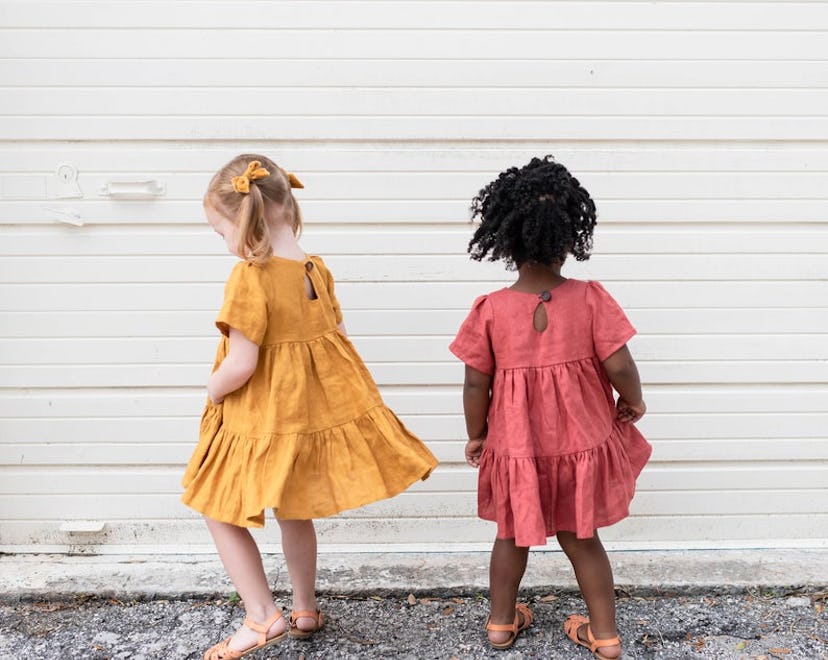 two kids wearing tiered linen dresses in mustard and pink