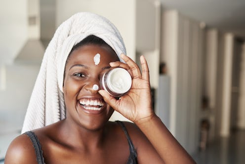 A woman uses a skincare cream for her face.