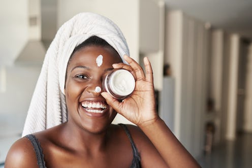 A woman uses a skincare cream for her face.