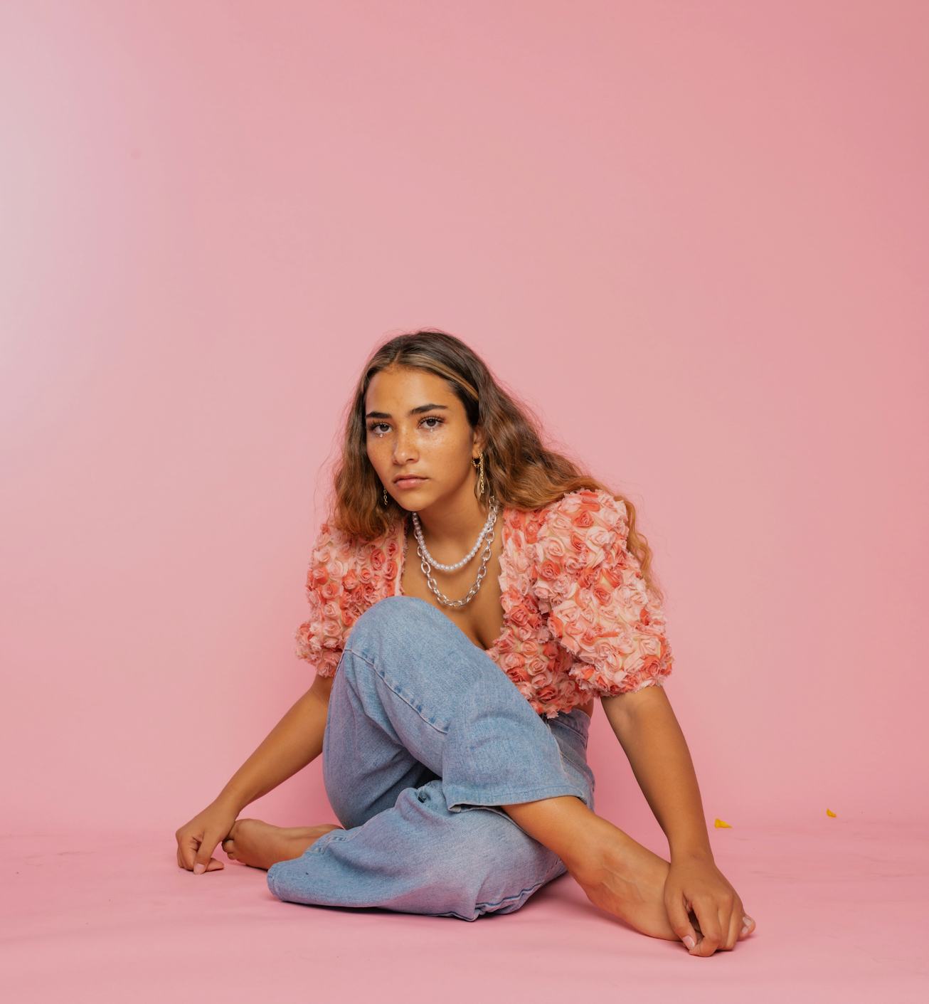 Sienna Mae Gomez sitting in front of pink screen. 