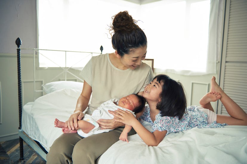Mom with young child and newborn, sitting on the bed 