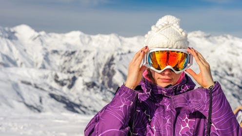 Skier adjusting goggles on slope