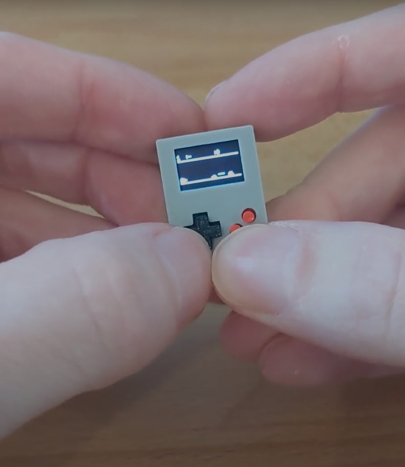 A pair of hands can be seen holding a very small Game Boy clone.