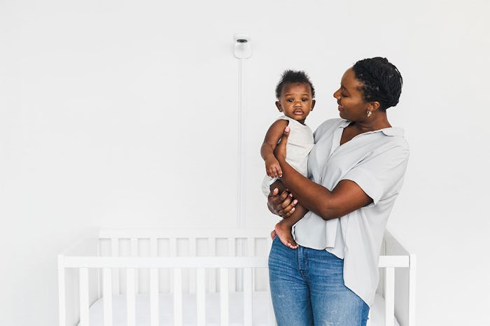 mom holding a baby in front of a crib