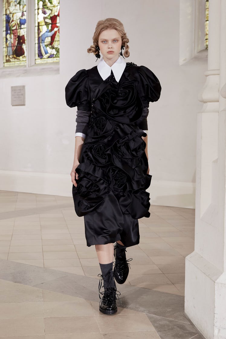 A model in a Simone Rocha black lace dress and black waistcoat at the London Fashion Week