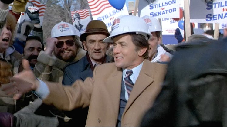 Martin Sheen as Greg Stillson, wearing a hardhat amidst a crowd on the campaign trail.