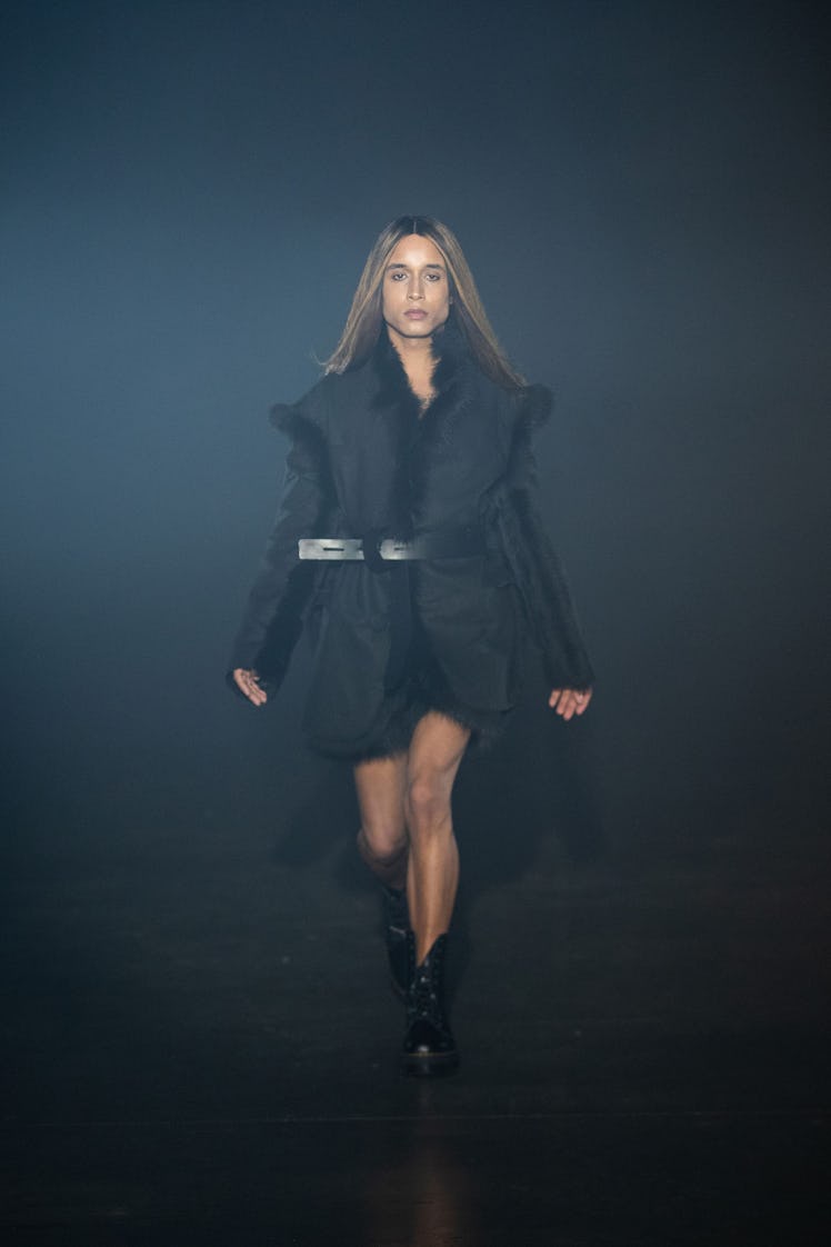 A model in an Art School gold black furry coat and black boots at the London Fashion Week