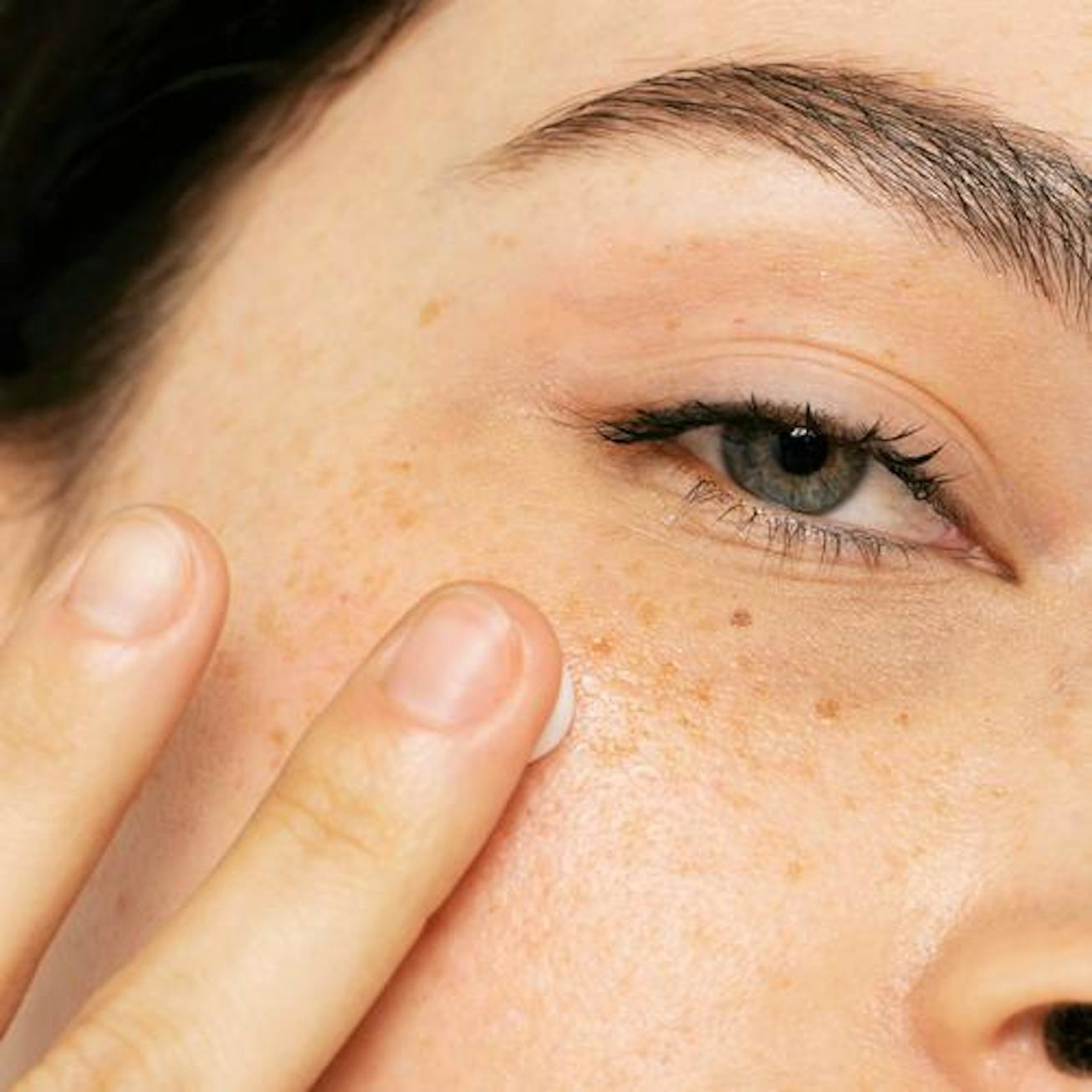 Model uses finger to apply product to under eye area