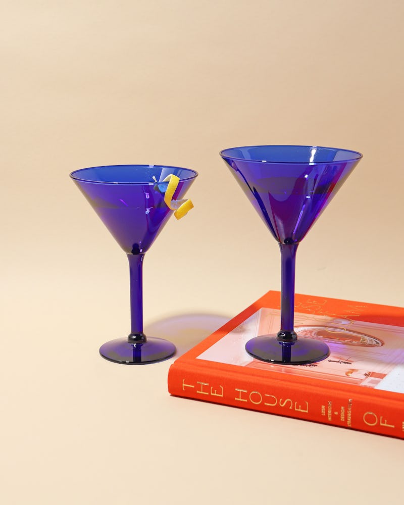 Deep blue martini glasses stacked atop a red book.
