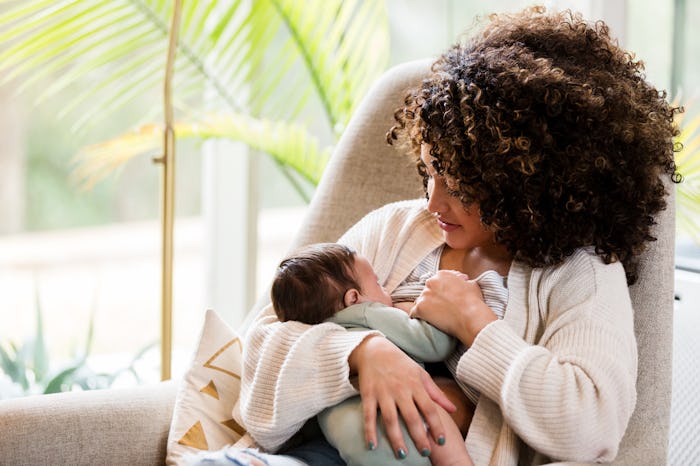 woman sitting in modern armchair, breastfeeding baby