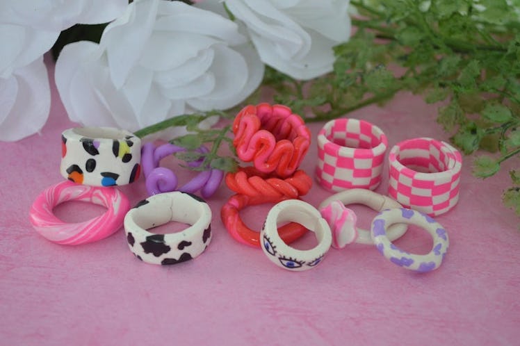 A collection of colorful and patterned chunky rings are presented on a cute pink table.
