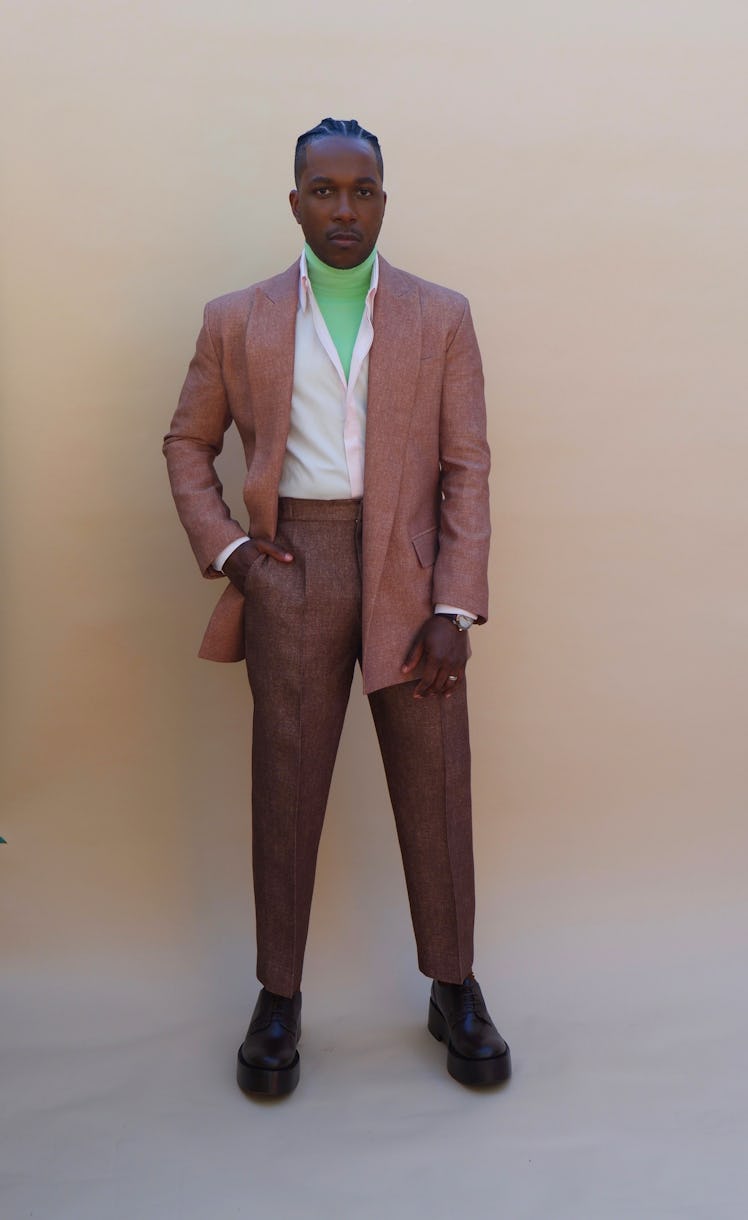 Leslie Odom Jr. in Valentino in a white shirt, green turtleneck, brown pants and beige blazer