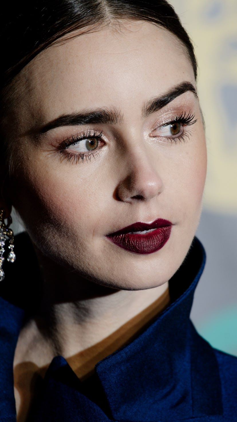 Lily Collins wears dark lipstick, along with a middle part, and her hair pulled back
