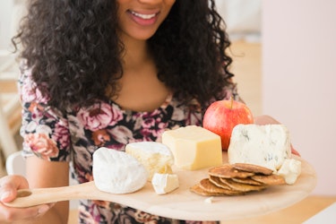 Mujer con tabla de frutas y queso