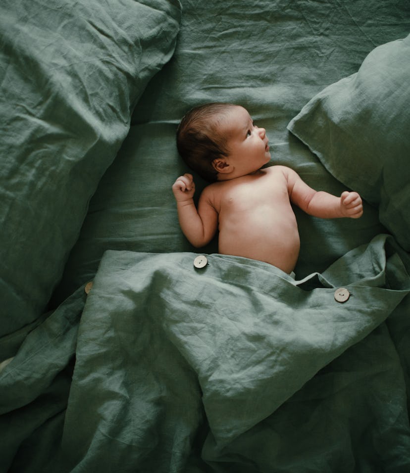 baby lying on bed with green sheets