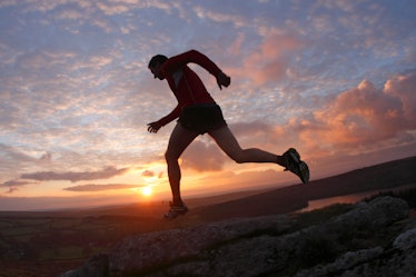 Man running across moors at sunset. 