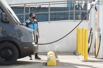 An Amazon driver charging a Rivian electric delivery van.