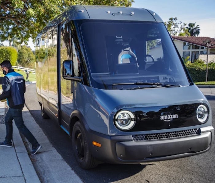 An Amazon delivery worker walks away from a Rivian electric van while holding a package