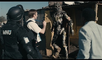 Sharlto Copley and military backup confronting an alien in a slum
