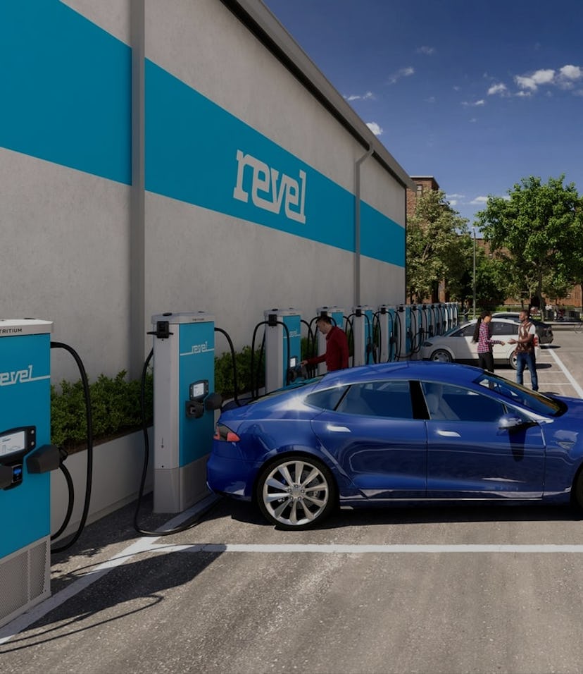 A blue Tesla sits docked at a Revel electric charging station.