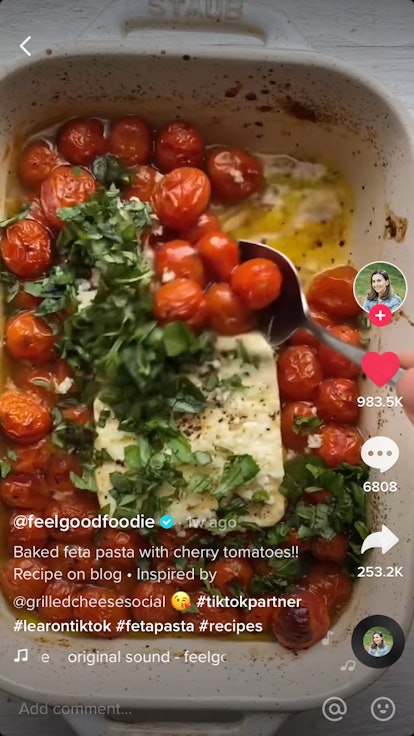 The traditional baked feta pasta recipe on TikTok has cherry tomatoes in a pan with olive oil and fe...