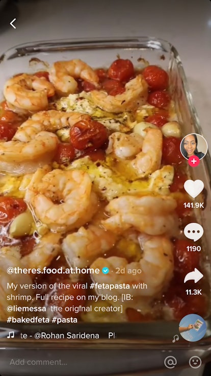 This feta pasta recipe includes cherry tomatoes, olive oil, and jumbo shrimp in a baking pan.