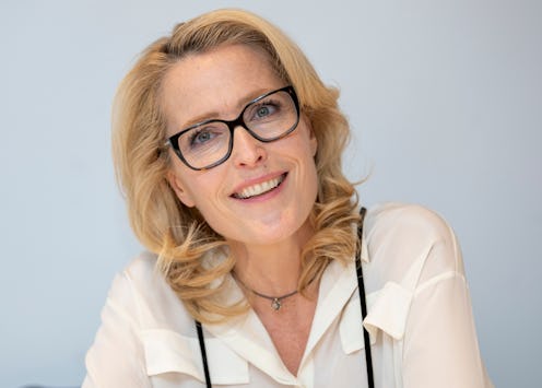 Gillian Anderson at a press junket for the crown wearing black rimmed glasses and a white shirt