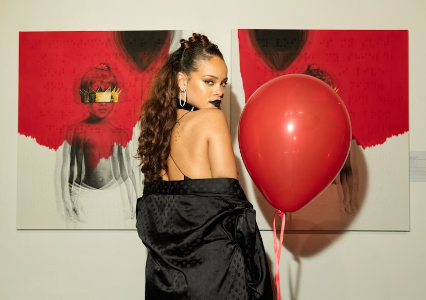 Rihanna stands against a white backdrop, wearing black lipstick