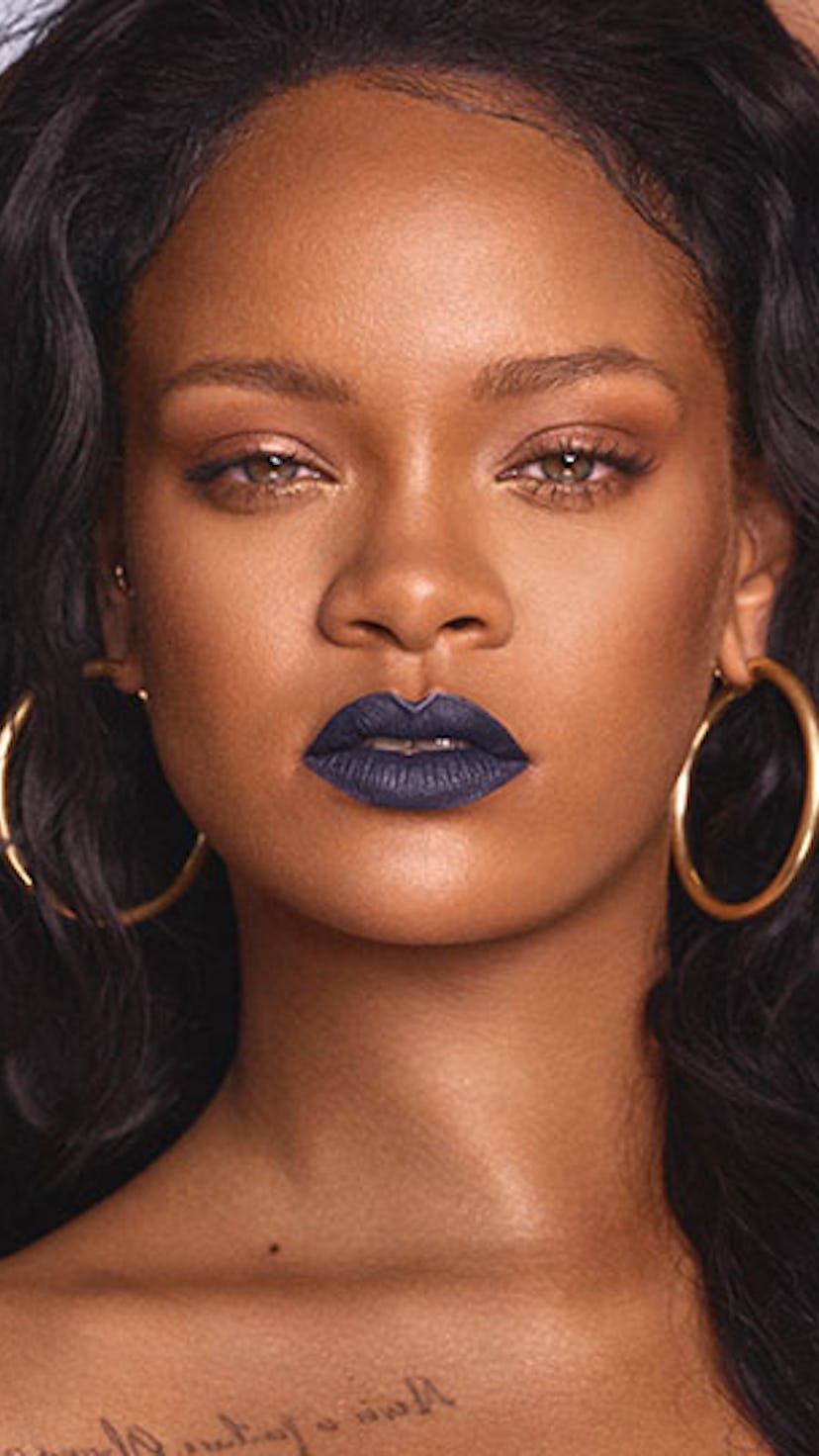 Rihanna with dark blue lipstick and gold hoop earrings for a Fenty Beauty campaign.