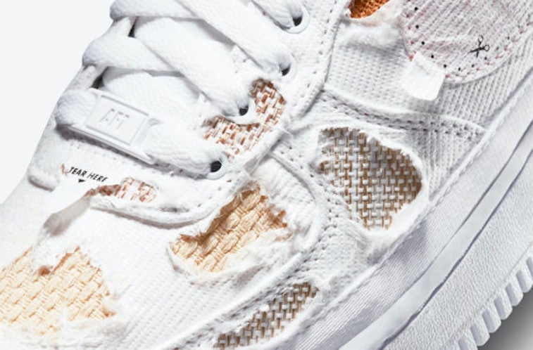 Ripped white sneaker with brown underlying fabric