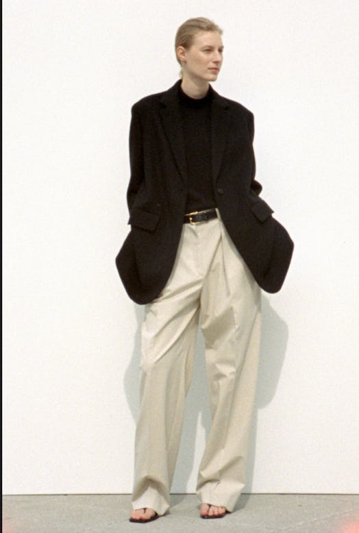 A woman in a black top and blazer, and beige wide leg chino pants