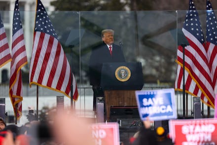 Donald Trump giving a speech for his supporters who are holding "Save America" and "Stand With Trump...