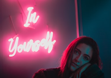 Young woman in front of "in yourself" neon sign