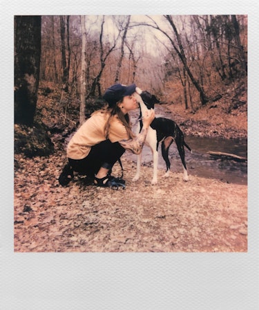 Polaroid of Julien Baker in the woods with her dog