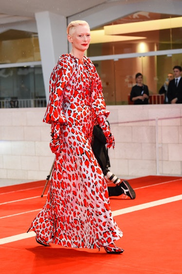Tilda Swinton walking the red carpet in a long white dress with red spots all over