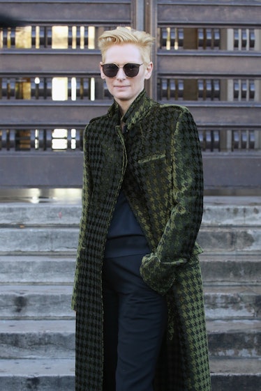 Tilda Swinton wearing a long sage green coat and sunglasses